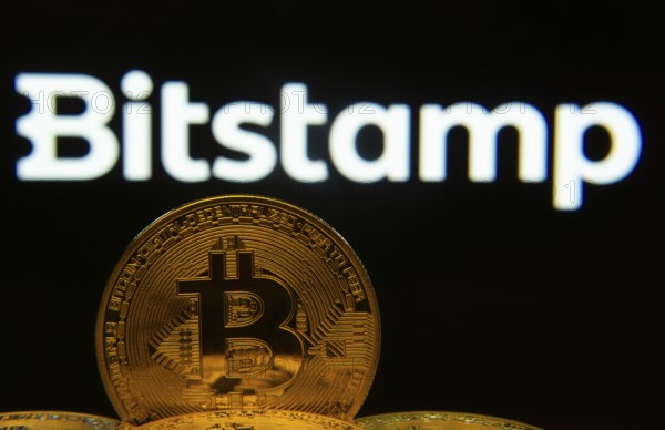 Dhaka, Bangladesh- 03 Sep 2025: Close-up of Bitcoin coins with the Bitstamp logo visible on a screen in the background