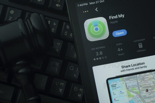 Dhaka, Bangladesh- 28 Oct 2025: An iPad displaying the Apple Find My app against a judge's gavel and dark keyboard background