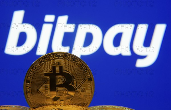Dhaka, Bangladesh- 26 Aug 2025: Close-up of Bitcoin coins with the bitpay logo visible on a screen in the background