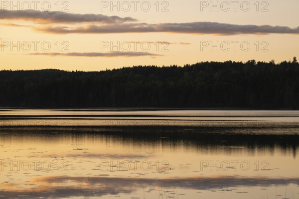 Clouds reflected on the water surface, forest lake, evening mood, at Sunne, Sweden