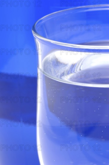 Glass with mineral water, small carbonated pearls on the edge of the glass, drinking water