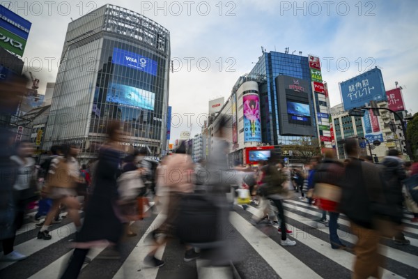 Crowd crossing zebra crossing on a large intersection, motion blur, back modern houses with colorful neon signs, long exposure, Shibuya Crossing, Shibuya, Tokyo, Japan