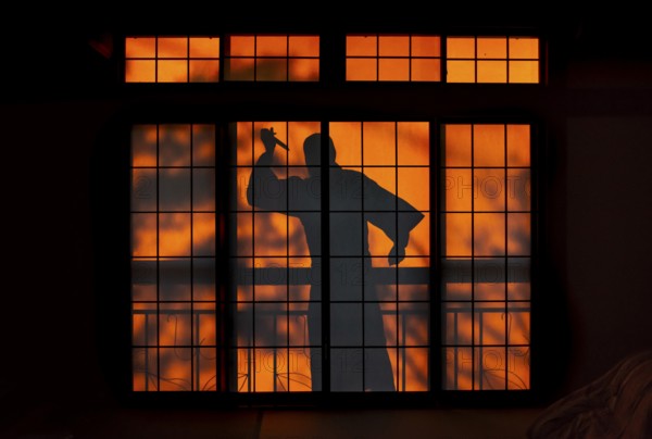 Shadow of a man, burglar with knife, assassin, ninja, on the balcony behind sliding shoji doors in a traditional Japanese house, Yamanouchi, Nagano, Japan