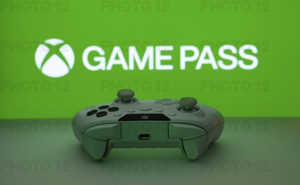 Dhaka, Bangladesh- 19 Sep 2025: A close-up of a white gamepad with the Xbox Game Pass seen on screen in the background