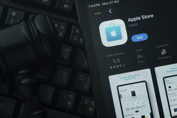 Dhaka, Bangladesh- 28 Oct 2025: An iPad displaying the Apple Store app against a judge's gavel and dark keyboard background