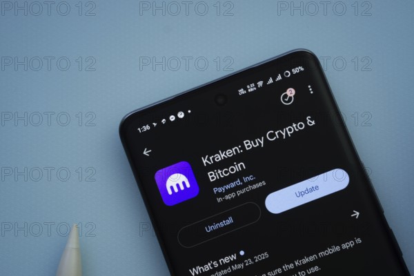 Dhaka, Bangladesh- 29 May 2025: On a blue surface, a smartphone displays the Kraken app within the Google Play Store