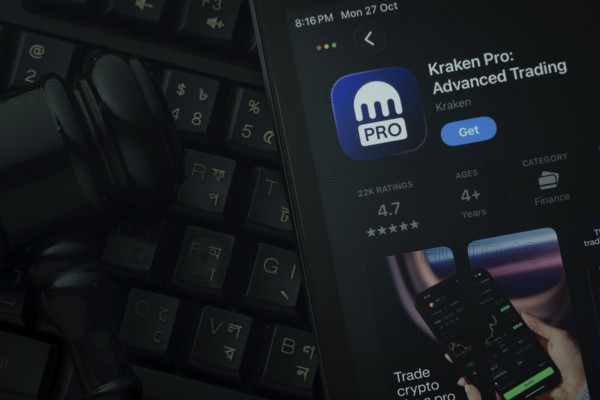 Dhaka, Bangladesh- 28 Oct 2025: An iPad displaying the Kraken Pro app against a judge's gavel and dark keyboard background