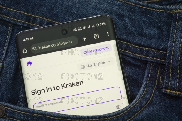 Dhaka, Bangladesh- 15 June 2025: A smartphone displaying the Kraken.com web interface peeks out of a denim pocket