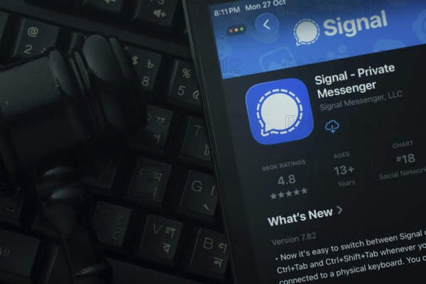 Dhaka, Bangladesh- 28 Oct 2025: An iPad displaying the Signal app against a judge's gavel and dark keyboard background