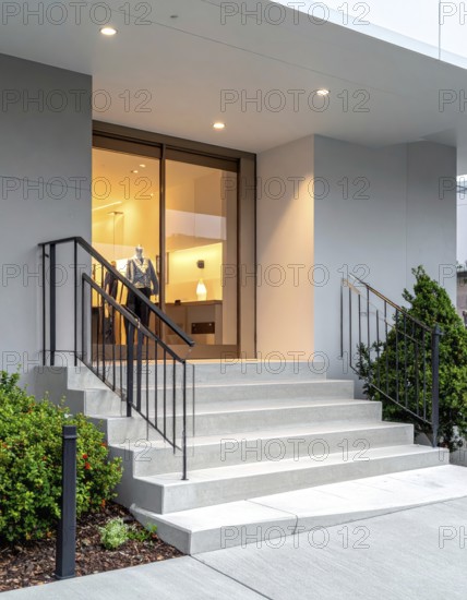 Modern building entrance with stairs, glass facade, and plants in warm evening light, empty storefront entrance with a gently stairs access, modern building with glass facade, blurred background, soft sunlight at evening, no people, AI generated
