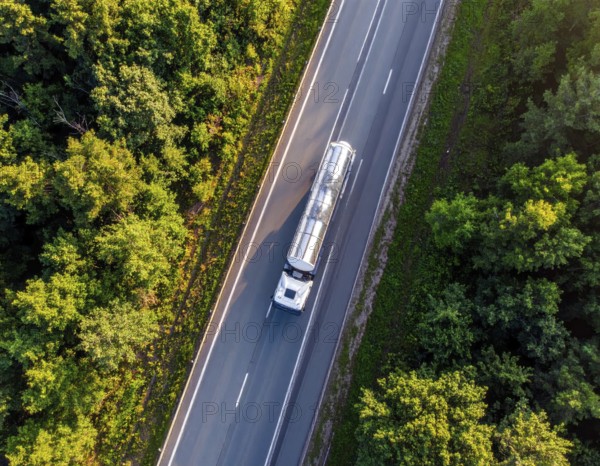 Petrol cargo truck lorry tanker driving on highway hauling oil products at sunrise, wide hilly landscape, AI generated