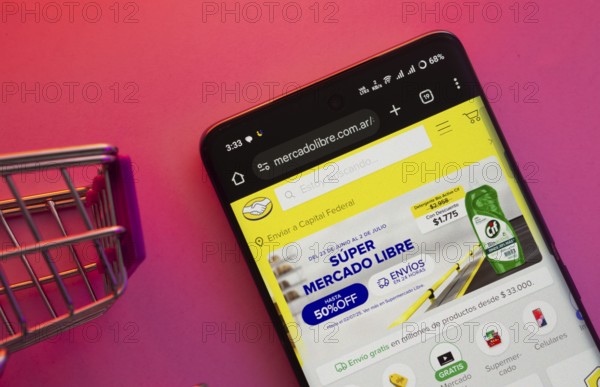 Dhaka, Bangladesh- 23 June 2025: A smartphone displaying the Mercado Libre website with a shopping cart is shown on a vibrant background