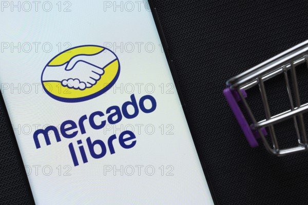 Dhaka, Bangladesh- 03 July 2025: A smartphone displaying the Mercado Libre logo next to a miniature shopping cart on a background