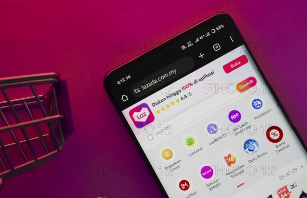 Dhaka, Bangladesh- 23 June 2025: A smartphone displaying the Lazada website with a shopping cart is shown on a vibrant background