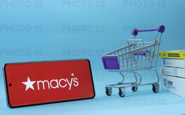 Dhaka, Bangladesh- 03 July 2025: Smartphone with Macy's logo next to a small shopping cart and boxes against a blue background