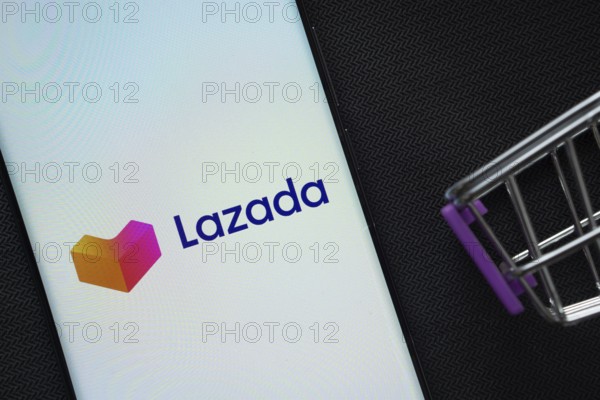 Dhaka, Bangladesh- 03 July 2025: A smartphone displaying the Lazada logo next to a miniature shopping cart on a background