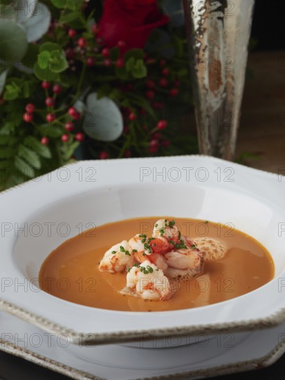 Creamy shrimp bisque soup with prawns, garnished with chives, on a white plate