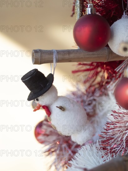 Festive snowman ornament with top hat decorating a cheerful christmas tree