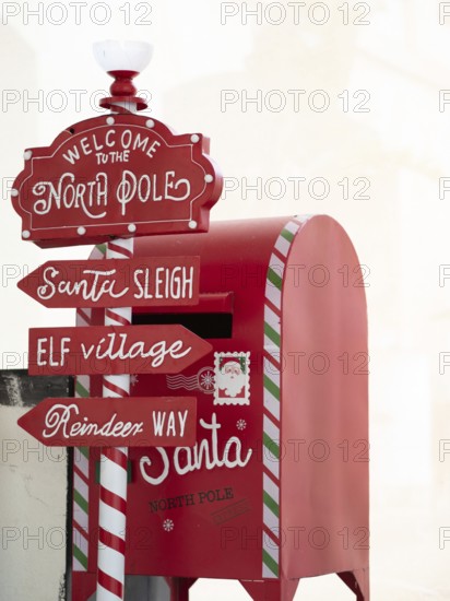 Red mailbox collecting letters to santa near directional signs to north pole