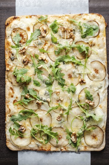 Gourmet flatbread preparing with pear, gorgonzola cheese, walnuts, and fresh arugula