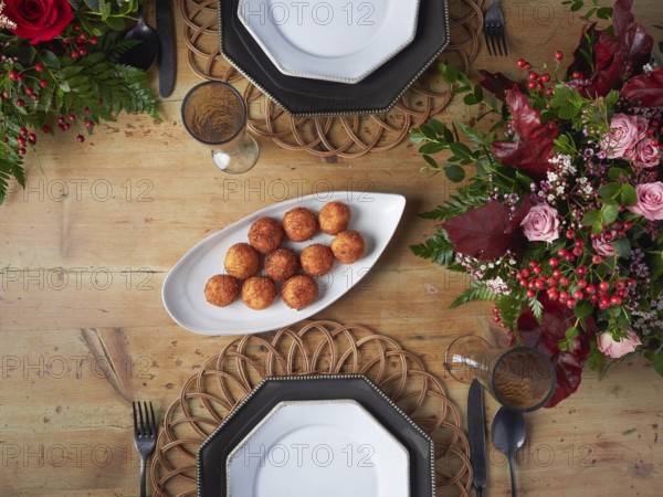 Crispy croquettes on an elegant white serving platter at a decorated dinner table