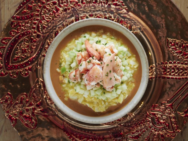 Gourmet lobster gazpacho with diced cucumber and chives, presented on an ornate platter
