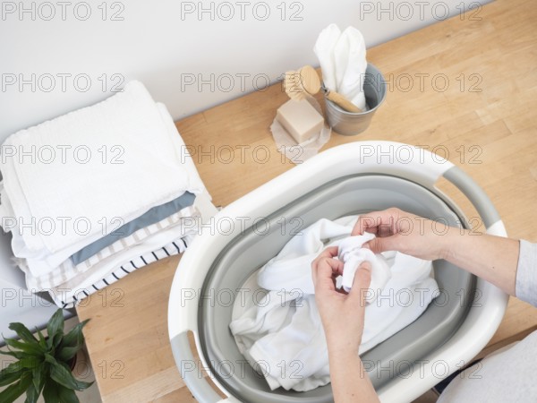 Woman inspecting clothes for stains before washing, preparing laundry in a sustainable way with natural soap and wooden brush