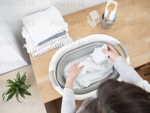 Housewife putting white clothes into a basin preparing laundry washing using natural soap bar and brush
