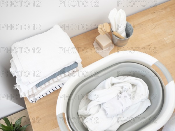 Eco-friendly laundry preparation featuring natural soap, brush, and folded clothes on a wooden surface, promoting sustainable washing practices