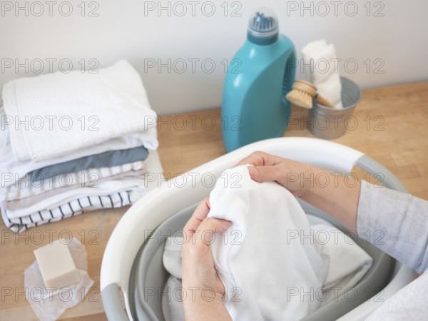 Woman checking white laundry before washing, with natural soap and ecological detergent