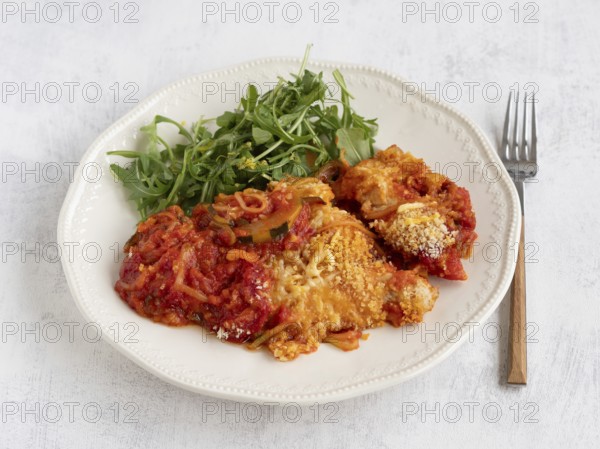 Enjoying a healthy and delicious meal of courgette spaghetti with tomato sauce, parmesan cheese, and a fresh arugula salad