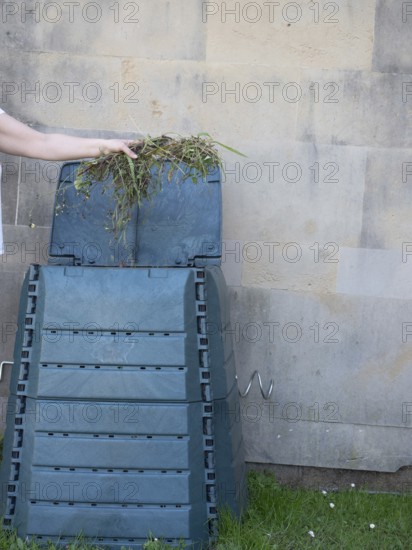 Gardener adding weeds to compost bin in urban garden, promoting sustainable gardening practices