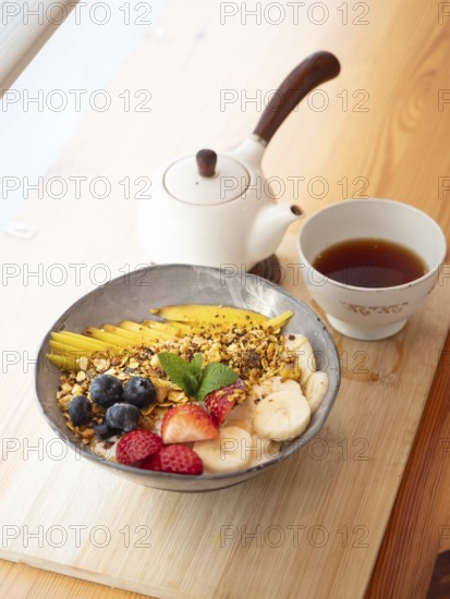 Oatmeal with granola, mango, banana, blueberries and strawberries served with tea