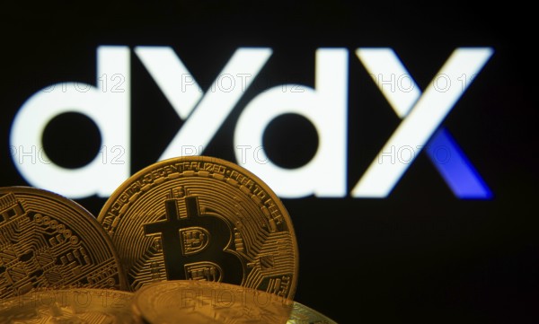 Dhaka, Bangladesh- 03 Oct 2025: Close-up of Bitcoin coins with the Dydx logo visible on a screen in the background