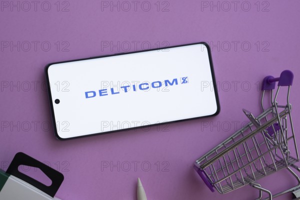Dhaka, Bangladesh- 03 Oct 2025: Smartphone displaying Delticom logo alongside a shopping cart on a purple background