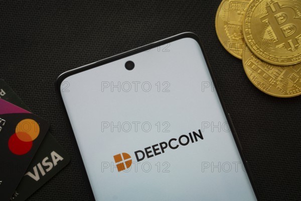 Dhaka, Bangladesh- 03 Oct 2025: Smartphone displaying Deepcoin logo surrounded by Bitcoin coins and payment cards