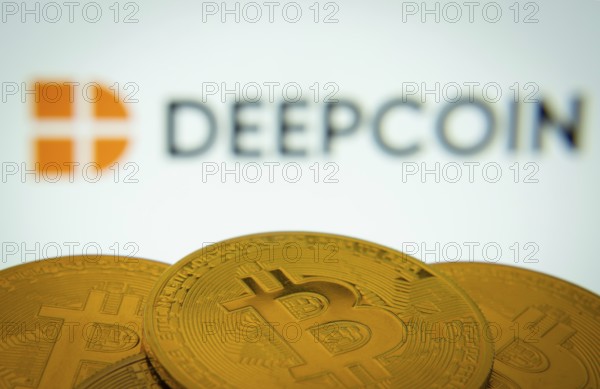 Dhaka, Bangladesh- 03 Oct 2025: Close-up of Bitcoin coins with the Deepcoin logo visible on a screen in the background