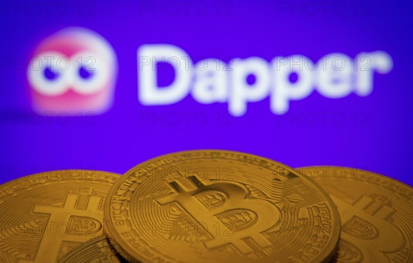 Dhaka, Bangladesh- 03 Oct 2025: Close-up of Bitcoin coins with the Dapper logo visible on a screen in the background