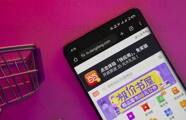 Dhaka, Bangladesh- 23 June 2025: A smartphone displaying the Dangdang.com website with a shopping cart is shown on a vibrant background