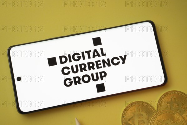 Dhaka, Bangladesh- 03 Oct 2025: Digital currency group logo on smartphone screen near Bitcoin coin and QR code on yellow background