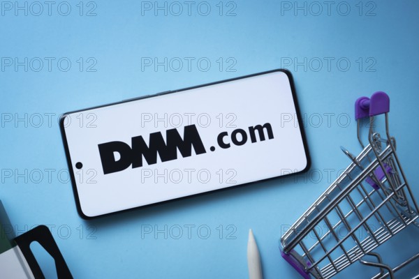 Dhaka, Bangladesh- 03 Oct 2025: Smartphone displaying Dmm.com logo with shopping cart on a blue background