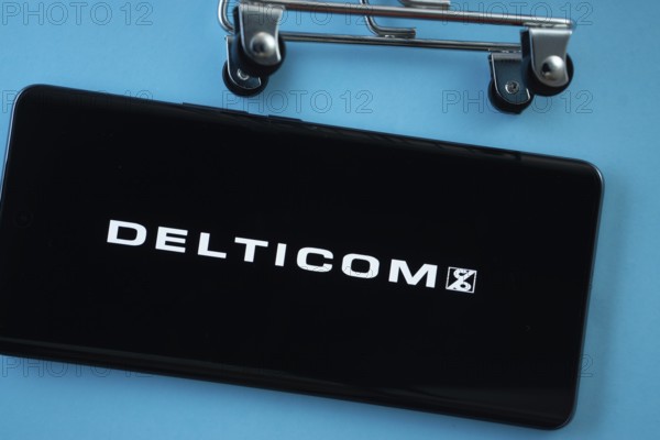 Dhaka, Bangladesh- 03 Oct 2025: Smartphone screen showing the Delticom logo with shopping cart wheels on a blue background