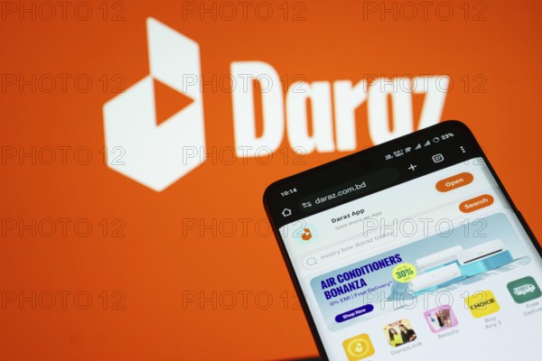 Dhaka, Bangladesh- 03 Oct 2025: Smartphone displaying Daraz web interface against Daraz logo background