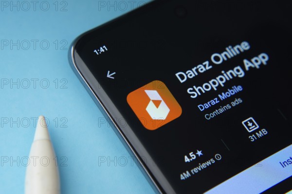 Dhaka, Bangladesh- 03 Oct 2025: On a blue surface, a smartphone displays the Daraz app within the Google Play Store