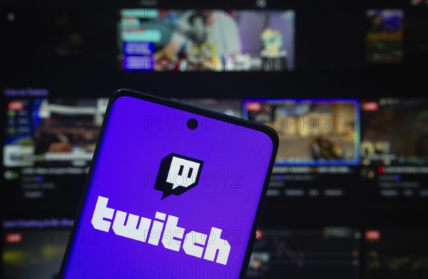 Dhaka, Bangladesh- 30 Sep 2025: Twitch logo is displayed on a smartphone screen, with the Twitch website visible on a computer screen in the background