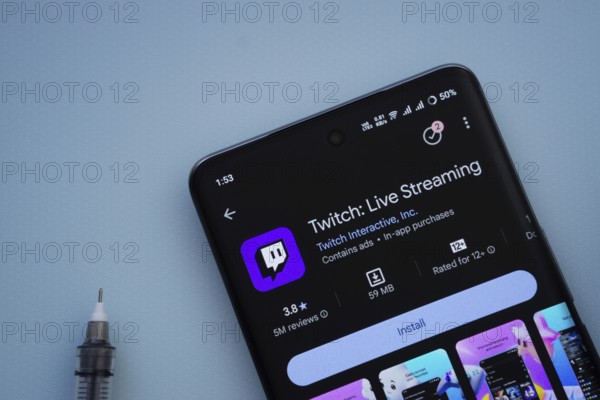 Dhaka, Bangladesh- 30 Sep 2025: On a blue surface, a smartphone displays the Twitch app within the Google Play Store