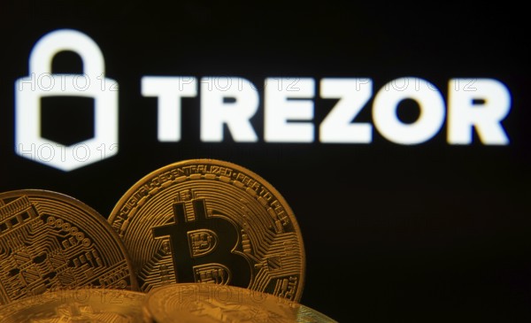 Dhaka, Bangladesh- 30 Sep 2025: Close-up of Bitcoin coins with the Trezor logo visible on a screen in the background