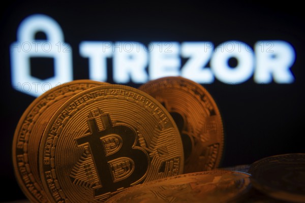 Dhaka, Bangladesh- 20 Sep 2025: Close-up of Bitcoin coins with the Trezor logo visible on a screen in the background