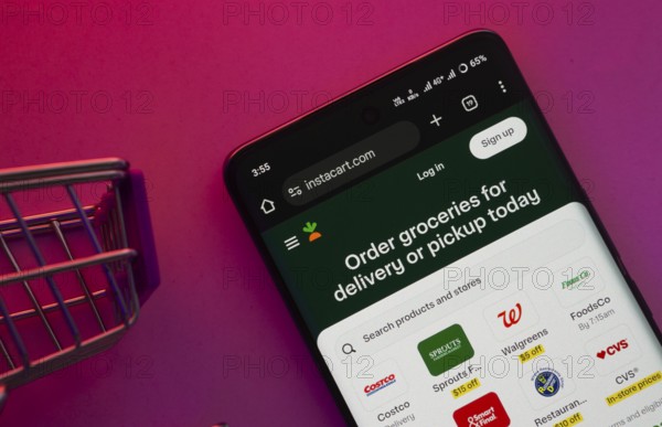 Dhaka, Bangladesh- 23 June 2025: A smartphone displaying the Instacart website with a shopping cart is shown on a vibrant background