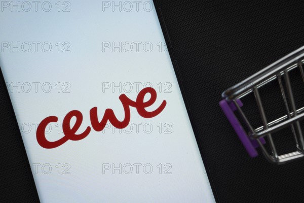 Dhaka, Bangladesh- 03 July 2025: A smartphone displaying the Cewe logo next to a miniature shopping cart on a background